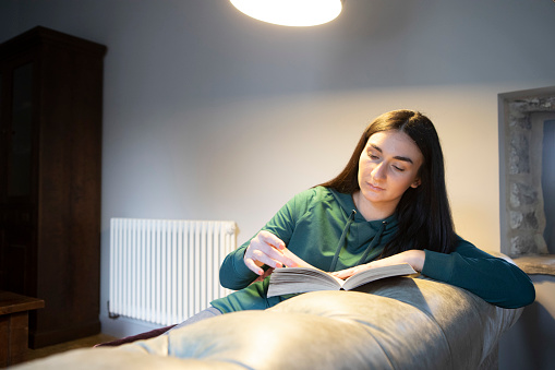 Female student in a green hoodie relaxing in a warm and comfortable home