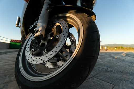 Close-up of a motorcycle wheel in the rays of the setting sun