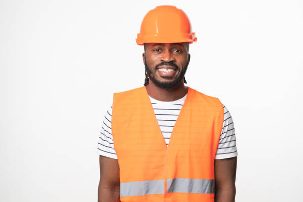 istock Happy cheerful african-american young man construction worker engineer architect in reflective orange vest and hardhat looking at camera smiling isolated in white background 1405430810