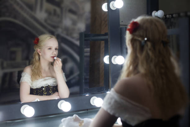 鏡の前の暗闇の中、楽屋で唇を赤く塗る若い女性女優 - mirror women reflection ghost ストックフォトと画像