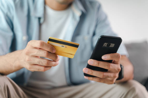 istock Man holding credit card and using smartphone for online shopping, internet banking, e-commerce, spending money, working from home concept 1405433315