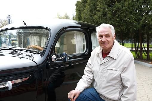 Portrait of senior man posing with vintage car