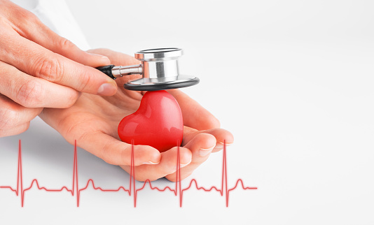 Doctor hands holding red heart and stethoscope. Cardiology, heart health and medicine concept. Copy space.