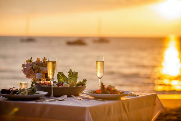 Romantic sunset dinner on the beach. Table set for two with luxurious food, glasses of champaign drinks in a restaurant with sea view. Summer love, romance date concept Romantic sunset dinner on the beach. Table honeymoon set for two with luxurious food, glasses of champagne drinks in a restaurant with sea view. Summer love, romance date on vacation concept. evening meal stock pictures, royalty-free photos & images