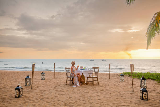 istock Woman sitting alone on table set with lantern for a romantic meal on beach 1405434208