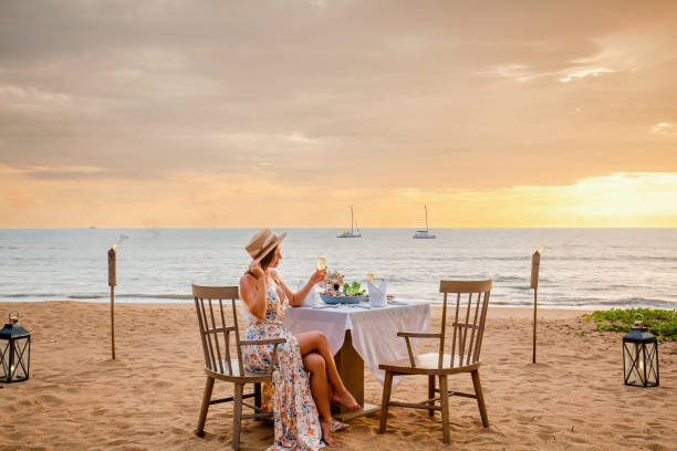 istock Woman sitting alone on table set with lantern for a romantic meal on beach 1405434221