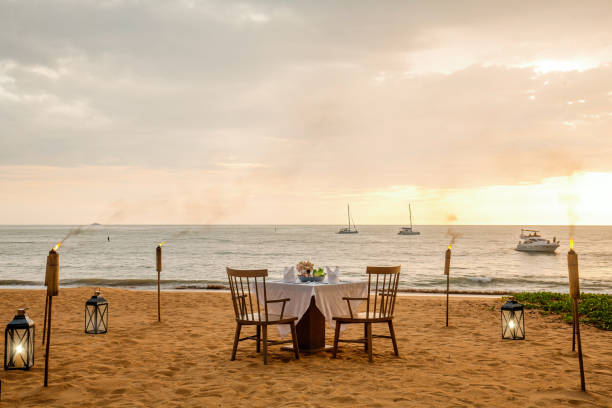 istock Romantic sunset dinner on beach. Table honeymoon set for two with luxurious food, glasses of champagne drinks in restaurant with sea view and yachts on background. Summer vacation or wedding concept 1405434228