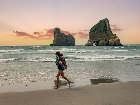 One woman run on the beach of Wharariki Beach and Archway Islands, Golden Bay, South Island, New Zealand.