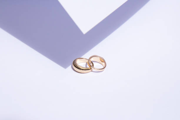 istock Two gold wedding rings on white background with contrasting shadows 1405435084