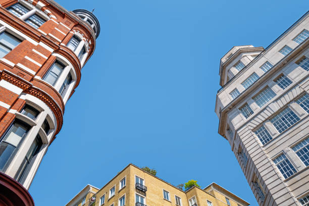 Generic London architecture in three styles and different colour brick and stone. Blue sky background with space for text.