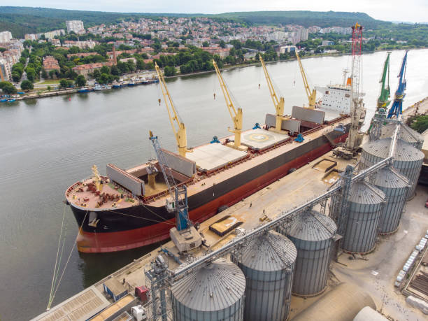 Loading grain into sea cargo vessel in seaport from silos of grain storage. Aerial view stock photo