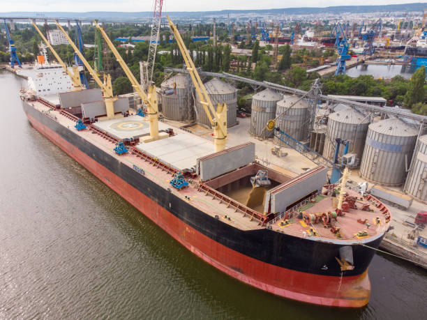 Loading grain into sea cargo vessel in seaport from silos of grain storage. Aerial view stock photo