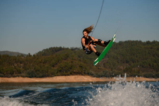 istock handsome healthy active man masterfully jumping over splashing wave on wakeboard 1405437226