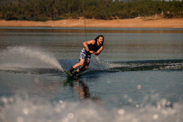 istock Athletic bearded guy holds rope and skilfully riding wakeboard on the river. 1405439632
