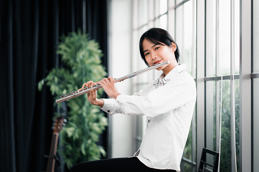 Young woman flutist performs on a musical instrument. Portrait of Beautiful Asian female artists, Classical musicians