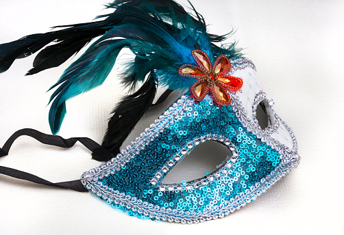 white and blue masquerade mask on white surface with copy space