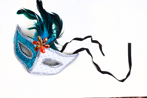 white and blue masquerade mask on white surface with copy space