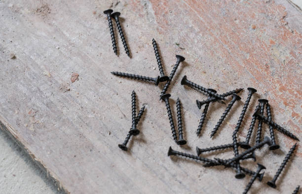 istock Black metal screws lie on the concrete floor. 1405443281