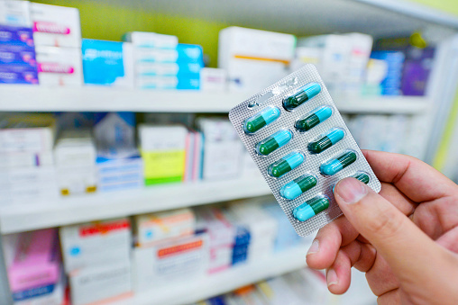 Hand holding medicine capsule pack at the pharmacy