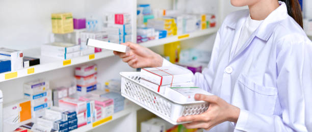 Pharmacist chemist woman standing refills the shelves with new stocks in pharmacy stock photo