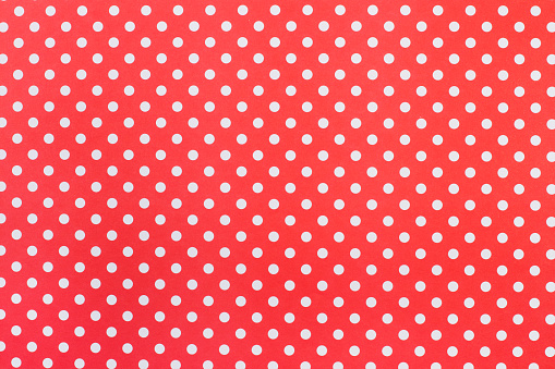 A red paper background with white polka dots
