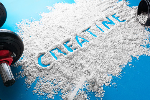 The word creatine written on a white powder. wellness concept.