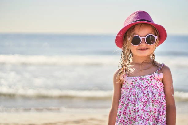 portrait of a girl with cap and sunglasses at the beach stock photo