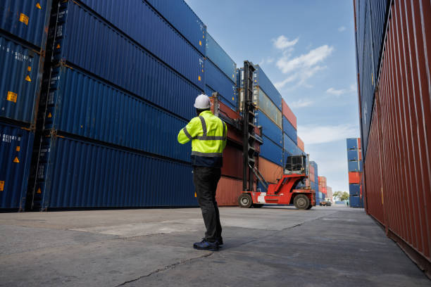 the african woker using walky talky comunicate with lifting container team with blue sky. Logistics transportation industry forklift handling container box loading stacker. back side worker man with wide angel view. el woker africano usando walky talky comunicarse con el equipo de contenedores de elevación con cielo azul. transporte logístico industria carretilla elevadora manejo de contenedores caja de carga apilador. hombre trabajador de la parte trasera con ampli
