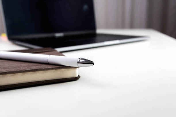 istock White office desk with notebook, pen and laptop. Selective focus. 1405455812