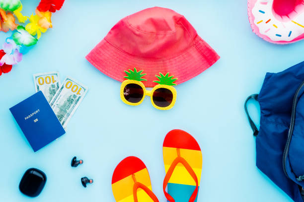 istock Top view summer vacation concept with all main necessary travel stuff. Backpack, bucket hat, funny sunglasses, flip flops, biometric passport, money cash, ear airpods. Bright Flat Lay with copy space 1405457753
