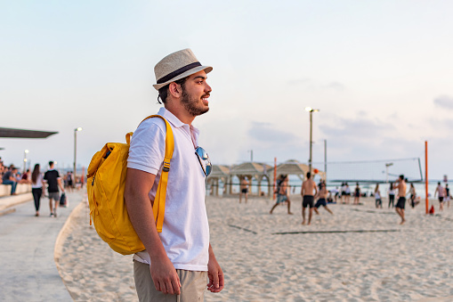 Man tourist with backpack in the beach enjoying summer season.