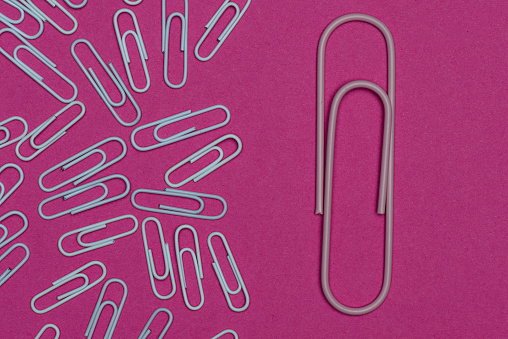Big paperclip and standard size paper clips on the purple background.