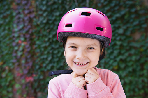 Happy girl putting bicycle helmet on.