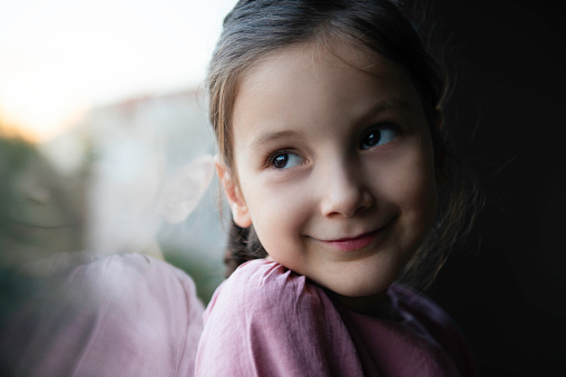 Little girl looking through window.