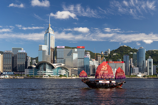 Hong Kong - June 23, 2022 : A junk boat with a slogan celebrating the 25th anniversary of Hong Kong's handover from Britain to China, on Victoria Harbour, Hong Kong.