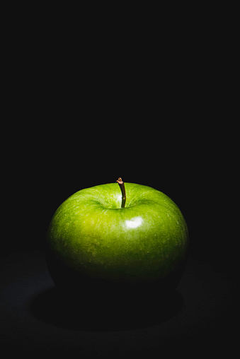 Close-up of wet apple against black background.