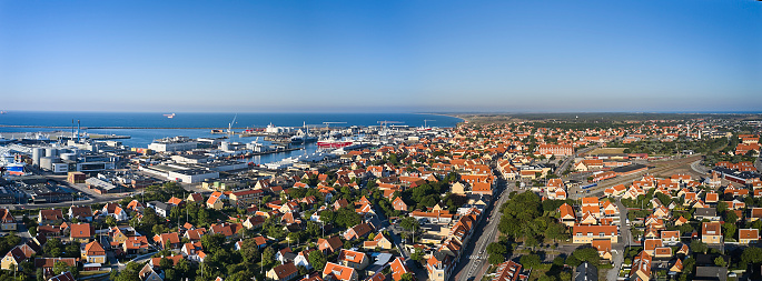 Aerial view of harbor with fishing ships. Sunny morning. Stitched wide angle image 180 degrees