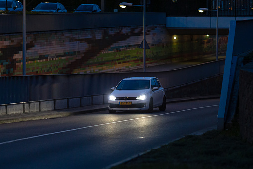 Wierden, Twente, Overijssel, Netherlands, april 11th 2022, close-up of a Dutch white 2009 Volkswagen Golf GTI station wagon coming out of a railway tunnel in Wierden at night - the Golf is a popular, top selling small family car made by German automaker Volkswagen AG since 1974