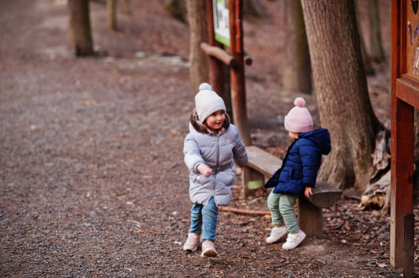 istock Sisters wear jacket and hat in early spring forest. 1405471932