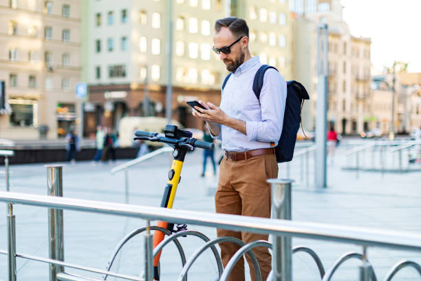 istock Young man renting electric scooter using smartphone 1405472021
