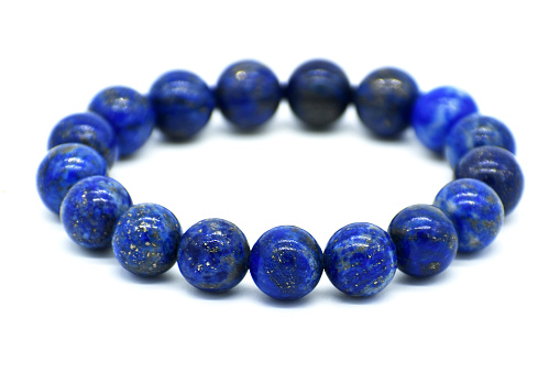 Lapis lazuli bracelet isolated on white background.  Selective focus at the front of the bracelet and leaving the back of it blurry.