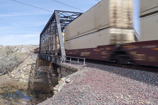 Victorville, California, USA - March 4, 2017: image of a BNSF Railway train shown crossing a truss railroad bridge spanning the Mojave River..