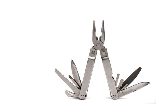 opened pliers of a multitool folding knife with visibly unfolded further applications like saw knife screwdriver and can opener on white background with copy space