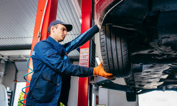 Expert specialist technician changes tires, tyres of lifted up car at auto service, wears uniform costume. Expert specialist technician changes tires, tyres of lifted up car at auto service, wears uniform costume. wheel cap stock pictures, royalty-free photos & images