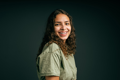 Smiling young woman with curly hair in studio