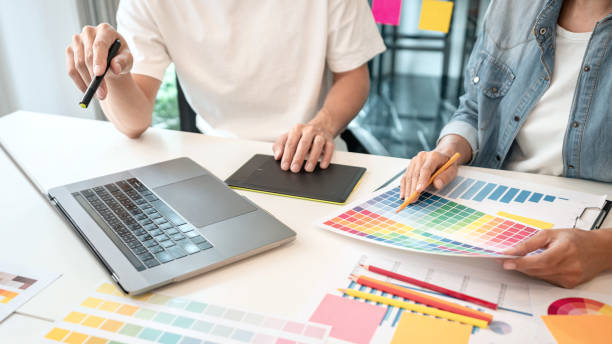 istock Two creative graphic designer team working on color selection and drawing on graphic tablet, Color swatch samples chart for selection coloring in inspiration to creativity at workplace 1405477922
