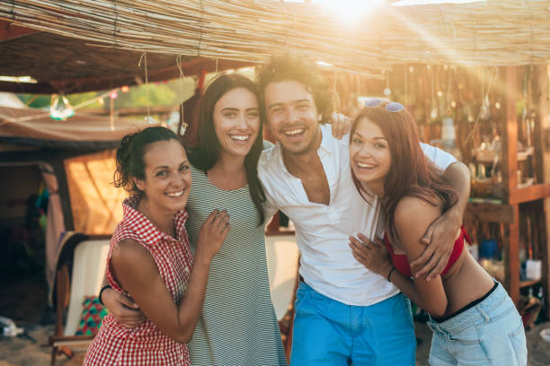 Group of happy young people outdoor. Friends having fun on a summer beach camp. Party on the beach. Friends laughing, happily smiling and looking at camera