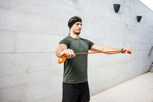 Young muscular man exercising with resistance bands