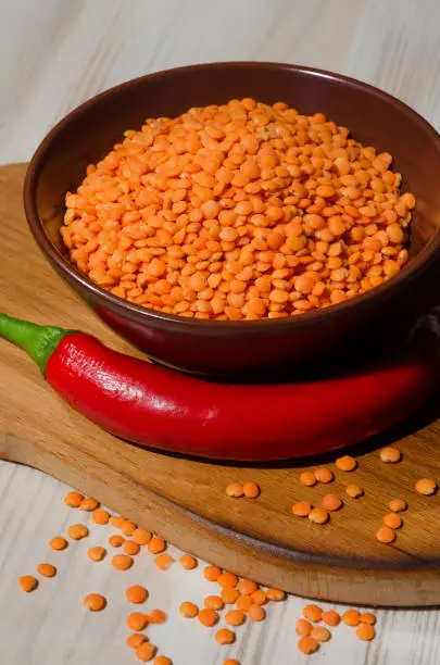 Photo of Lentils in a bowl and with red pepper on the board.