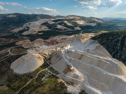 Aerial drone view of career in Europe at summer sunset, crushed stone quarry, beautiful nature round, some excavators, diggers inside